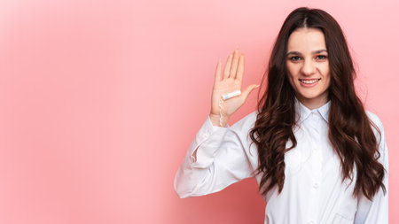 A studio shot of a girl holding a tampon in her hand in a menstrual applicator. Space for the text. The concept of feminine hygiene.の写真素材