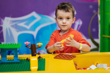 Close-up of a boys child playing with colorful plastic bricks at a table. The kid has fun and builds from bright constructor cubes. Early learning. Educational toysの写真素材