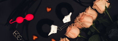 Various sex toys set on a black background. Top view. Spring. Roses.Horizontal wide photo subtitle, cover. copy-spaceの写真素材
