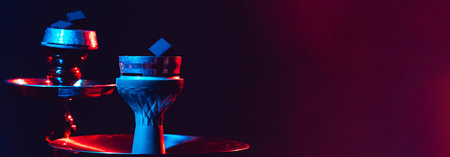 Modern hookah, shisha on a black background with colored lighting and smoke. Close-up and place for...