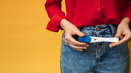 Close-up of female hands holding a positive pregnancy test. The concept of pregnancy, motherhood. A place for your text.の写真素材