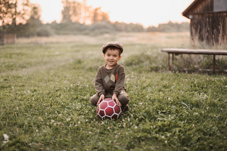 A boy is playing with a soccer ball in the fresh air in the countryside. The boys sincere smile. Childhood in the fresh air.の写真素材
