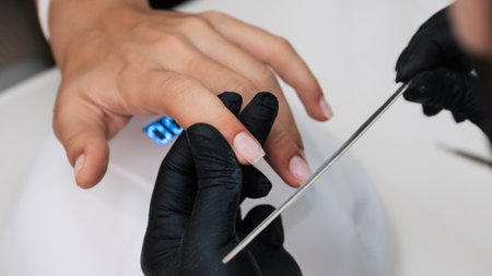 A manicure master gives a manicure to a girl in the salon. Nails are filled with a nail file. Close-upの写真素材