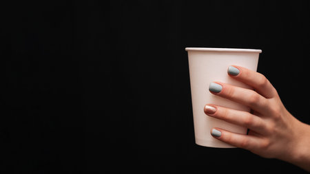 A womans hand with a neat manicure holds a plastic cup. A place for your text or advertisement.の写真素材