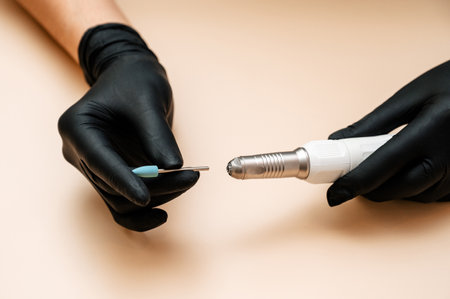 A machine for professional hardware manicure in a womans hand on a light background. Equipment for the nail service master. Cosmetic procedures.の写真素材