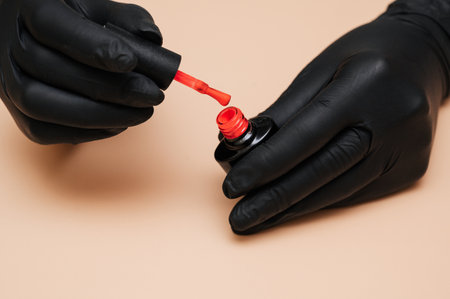 Close-up. The manicure master holds in his hands a tube of nail polish on a light background.の写真素材