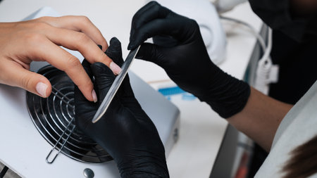 Close-up of a manicure master sawing a nail file. The concept of salon professional manicureの写真素材