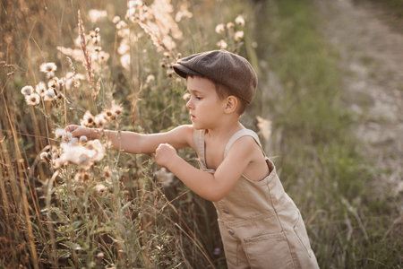 A happy child boy spends his day actively in the field in the village on a warm summer day. An authentic snapshot of childhood in the countryside.の写真素材