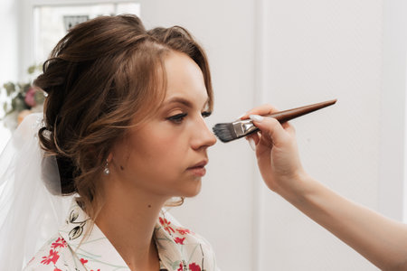 Shooting in a beauty salon. makeup artist makes a wedding makeup for a young girl.の写真素材