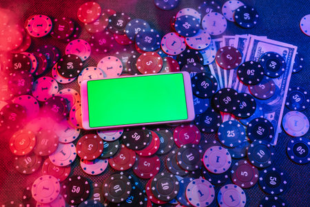 The concept of an online casino: betting chips and a smartphone with a green background with a copy space. Top view. Smoke added to the photoの写真素材