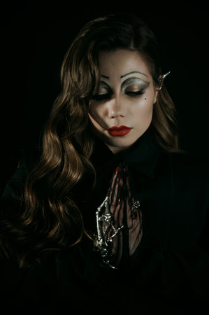Portrait of a young woman in a Gothic gloomy image of a witch or vampire. Halloween costume. Vertical photo.の写真素材