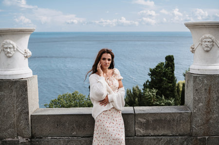 A young tourist girl in a vintage white dress poses near the palace. The sea is behind her. A snapshot from recreation and excursionsの写真素材