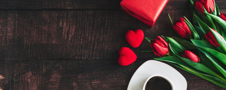 Bouquet of red tulips on a wooden background with a Cup of coffee. Spring flowers. Mothers day background. Horizontal wide photo subtitle, cover. copy-spaceの写真素材