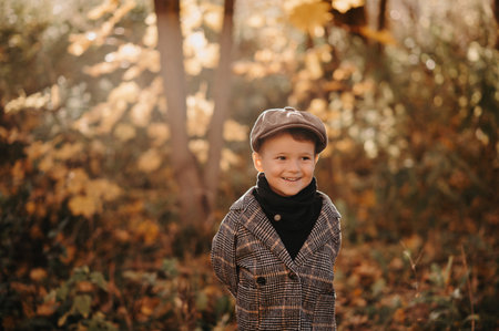 Portrait of a happy child boy walking among golden trees in the autumn in the park.の写真素材