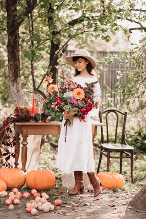 A beautiful happy woman holds a bouquet of flowers and herbs in her hands. Autumn moodの写真素材