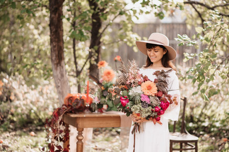 A beautiful happy woman holds a bouquet of flowers and herbs in her hands. Autumn moodの写真素材