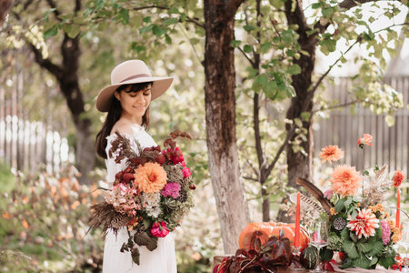 A beautiful happy woman holds a bouquet of flowers and herbs in her hands. Autumn moodの写真素材