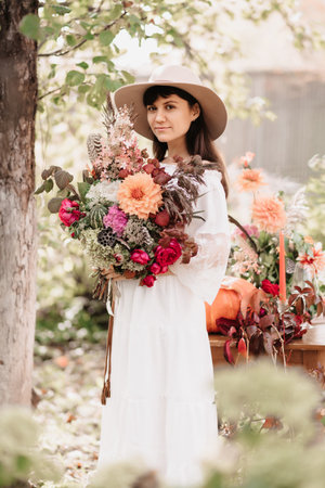A beautiful woman holds a bouquet of flowers and herbs in her hands. Romantic moodの写真素材