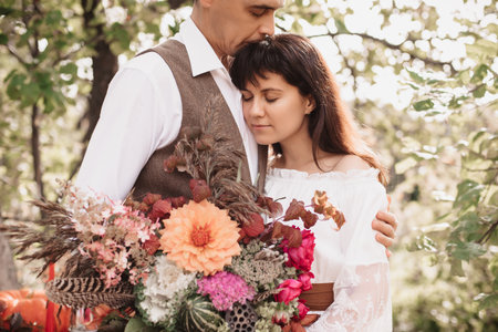A man embraces a girl with a bouquet in her hands. Gentle embrace of loversの写真素材