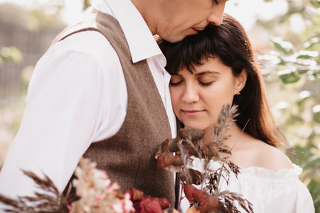 A man embraces a girl with a bouquet in her hands. Gentle embrace of loversの写真素材