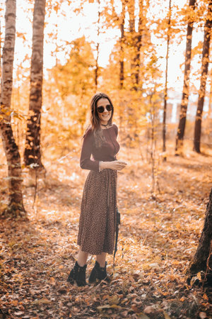 A young woman walks in the autumn city park. Positive emotions. Unity with nature.の写真素材