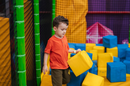 A boy child is playing in a game entertainment nursery. He plays with soft large cubes. Active pastime in the amusement park.の写真素材
