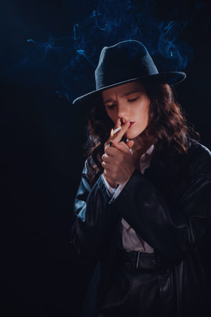 Dark noir portrait of a female detective lighting a cigarette. Private detective, spy, investigation concept.の写真素材
