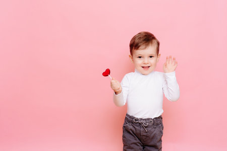 studio portrait of a happy boy with a heart-shaped lollipop.の写真素材