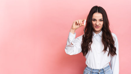 A young woman holds a menstrual swab in her hands. Pink background. Space for text. The concept of feminine hygiene.の写真素材