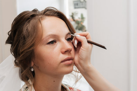Shooting in a beauty salon. makeup artist applies makeup to the brideの写真素材