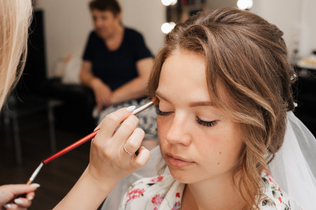 Shooting in a beauty salon. makeup artist prepares the bride before the wedding in the morningの写真素材