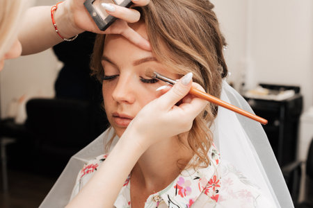Shooting in a beauty salon. makeup artist prepares the bride before the wedding in the morningの写真素材