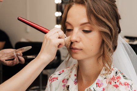 Shooting in a beauty salon. makeup artist applies makeup to a young beautiful girl bride.の写真素材