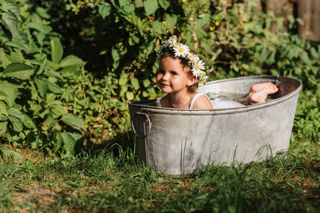 A baby smiling girl bathes in a childrens bathroom standing in the garden, on a hot sunny summer dayの写真素材