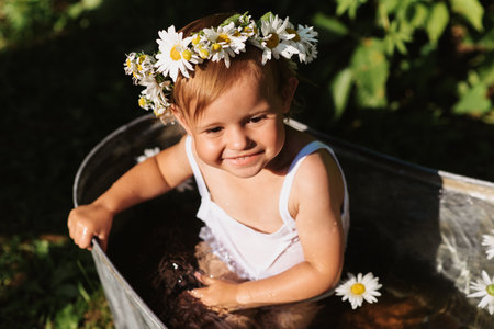 A cute smiling baby is bathing in a bathtub standing in the garden, on a hot sunny summer dayの写真素材