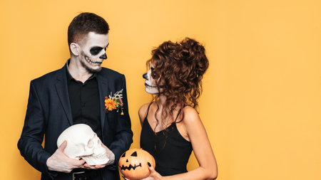 Halloween celebration. A studio shot of a young couple in festive Halloween costumes and with makeup on their face. A place for your text, advertising.の写真素材