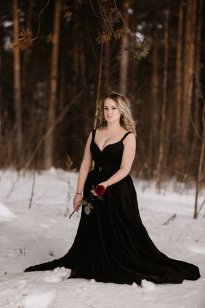 Portrait of a young girl in the image of a dark witch with a scarlet rose in her hands. An image for Halloween. Mysticismの写真素材