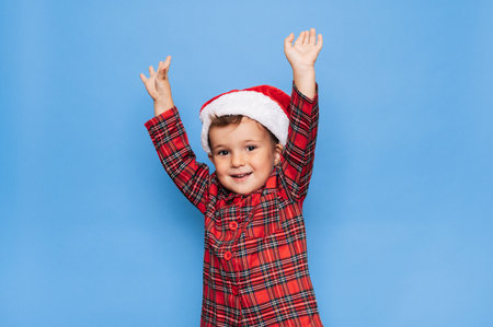 A studio shot of a happy boy in Christmas pajamas, fooling around and smiling. The concept of holidays.の写真素材