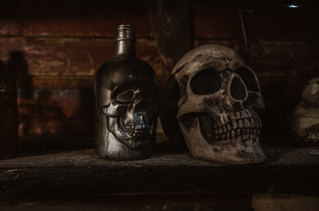 An old glass bottle stands on a dark shelf in the hold of the ship next to the skull.の写真素材