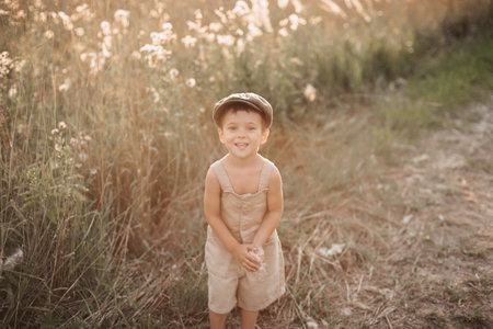 A child boy walks in a field in the village on a warm summer day. An authentic snapshot of childhood in the countryside.の写真素材