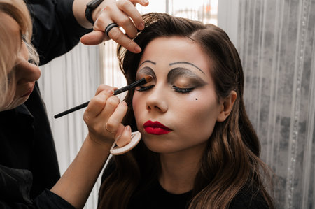 A makeup artist makes art makeup for a young girl in a beauty salon. The concept of celebrating Halloween. Unusual makeup.の写真素材