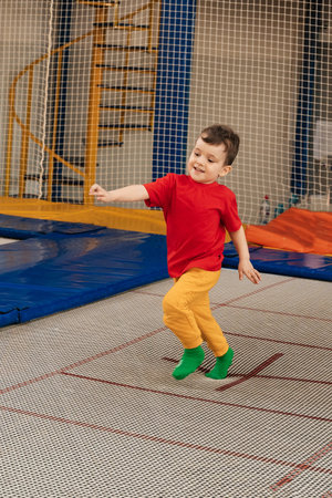 A happy boy runs and jumps on a trampoline in an entertainment center. Childhood. Active leisure.の写真素材