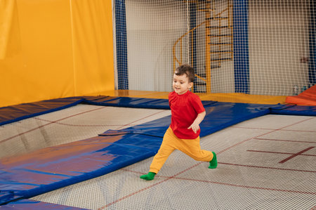 A happy boy runs and jumps on a trampoline in an entertainment center. Childhood. Active leisure.の写真素材