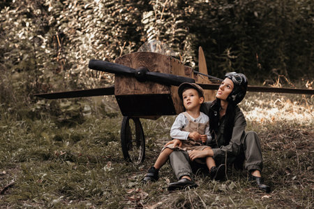 A young boy aviator together with his mother aviator in a homemade airplane in a natural landscape Authentic mood of the picture. Hugs of mother and son. Cartography. Vintage.の写真素材
