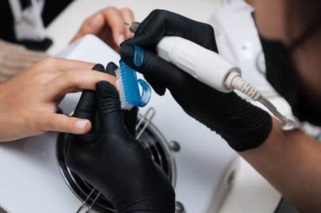 Hardware manicure. Close-up of a manicure master filing gel polish with a nail grinder with a cutter.の写真素材