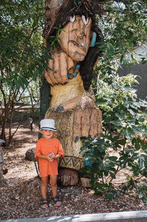 A little boy is walking in the park. A child with his parents explores local attractions, garden figures and sculptures.の写真素材