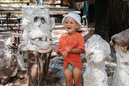 A little boy is walking in the park. A child with his parents explores local attractions, garden figures and sculptures.の写真素材