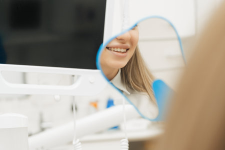 Close up of beautiful young woman look in mirror show healthy white teeth after dental treatment good oral careの写真素材