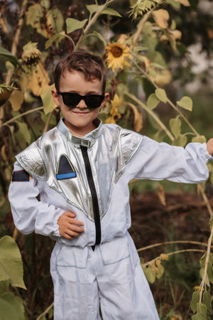 A little boy in an astronaut costume is playing outside on a sunny day. Vertical photo.