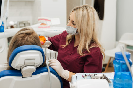Close-up partial view of dentist using dental curing UV lamp on teeth of patientの写真素材